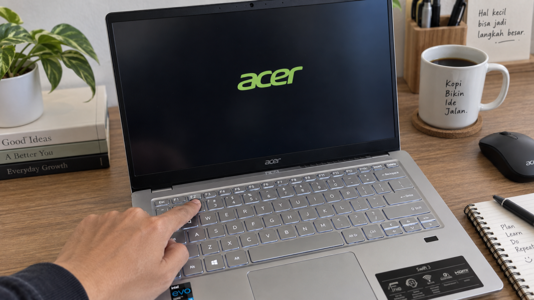 Tangan menekan tombol F2 pada keyboard laptop Acer saat logo Acer muncul pada proses startup.